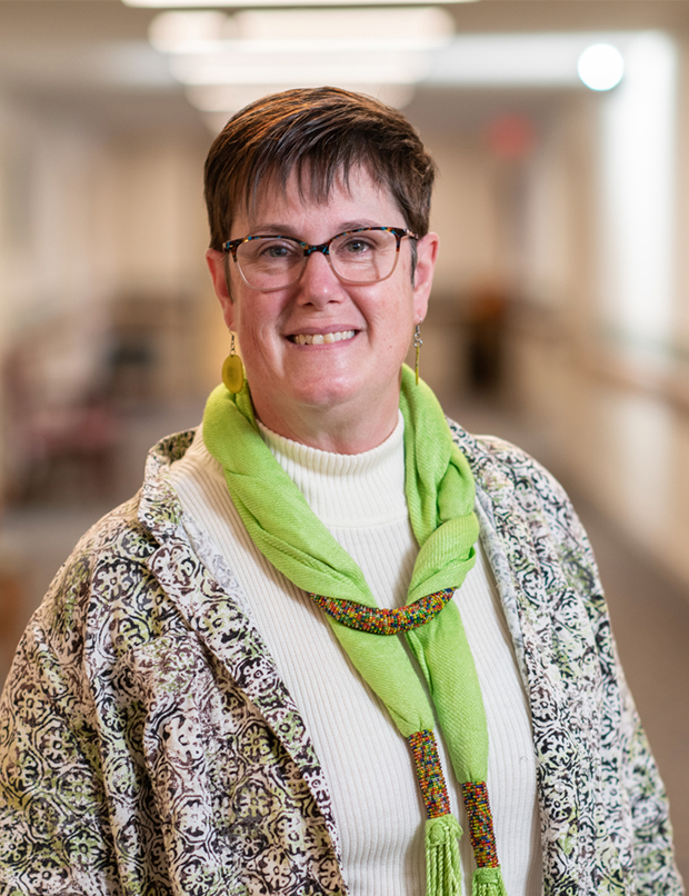 Woman with green scarf and turtle neck and glasses smiling