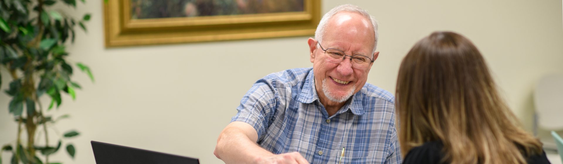 a man in a plaid shirt is smiling while talking to a woman