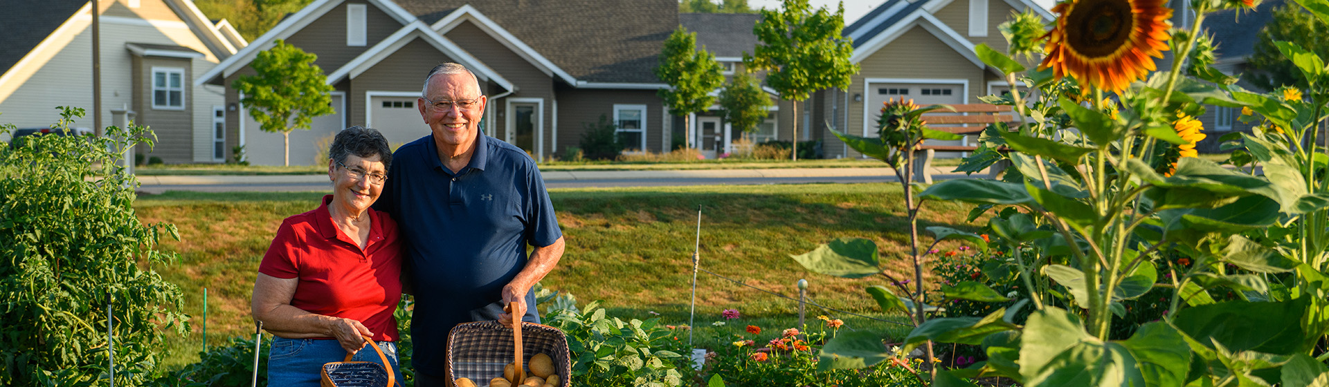 a man and woman standing in front of a house holding baskets
